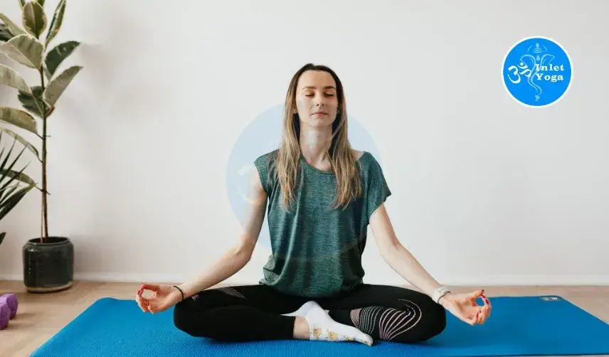 Woman getting meditation in lotus pose on blue yoga mat at Inlet Yoga studio in Manasquan NJ